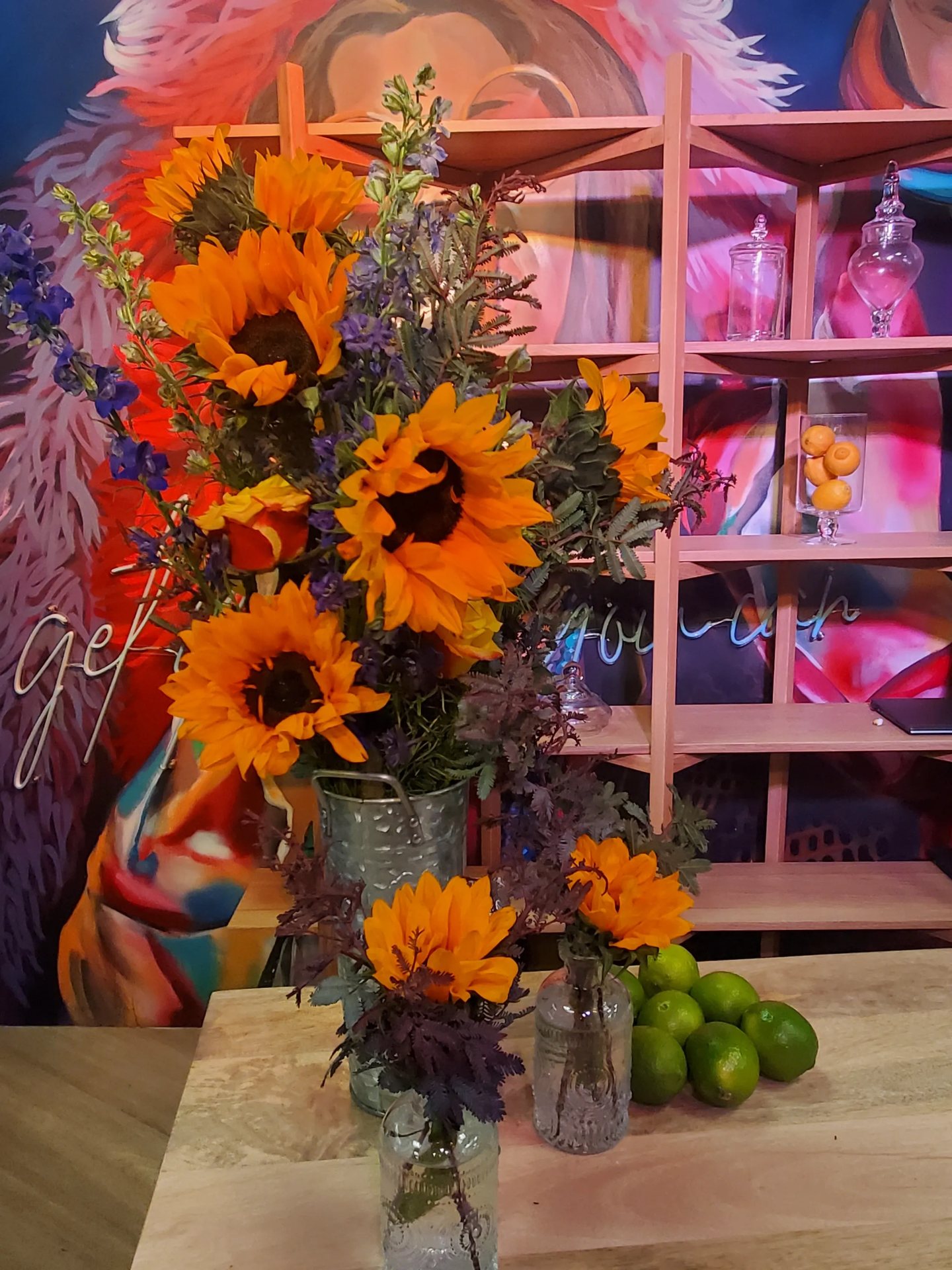 Sunflower and blue delphinium arrangements in a bucket at an Austin event bar